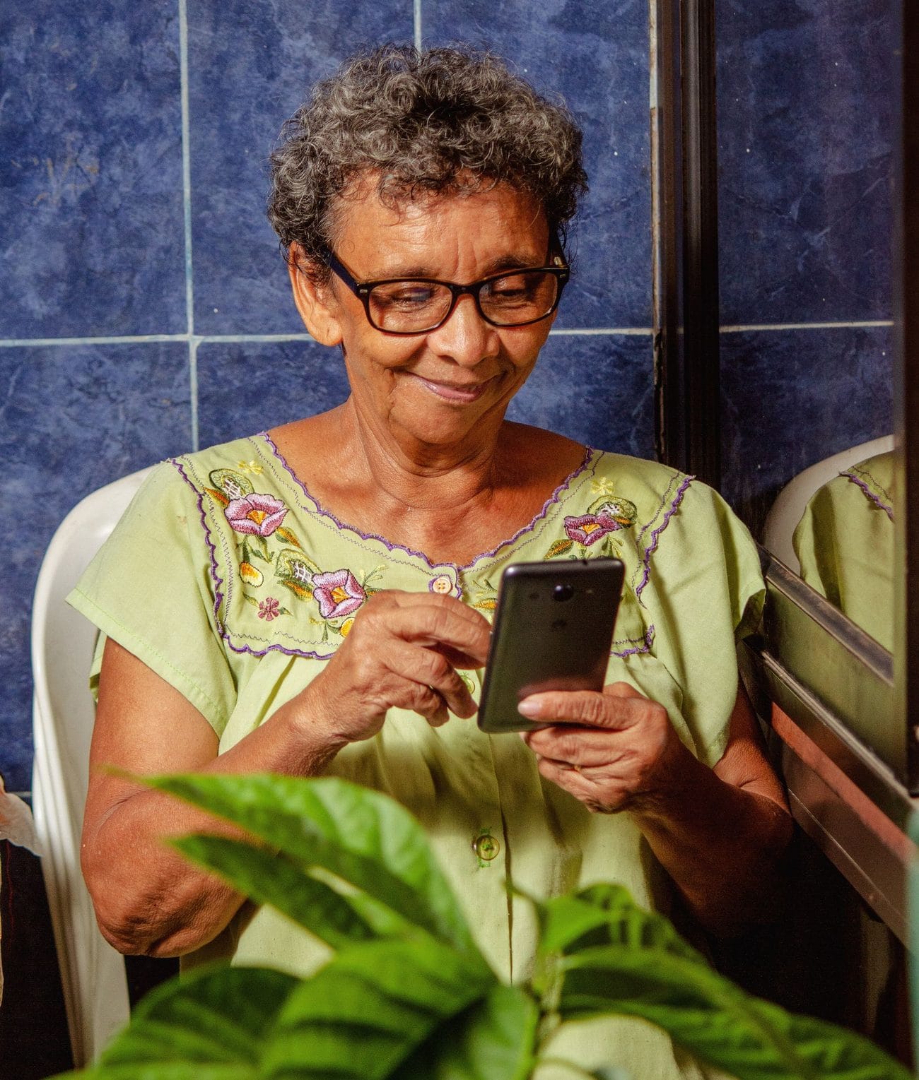 Senhora sorrindo enquanto usa o celular
